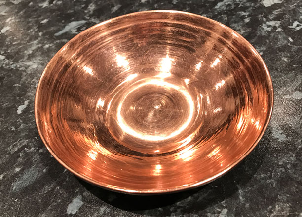 A shiney copper tank in the shape two desert bowls joined together.